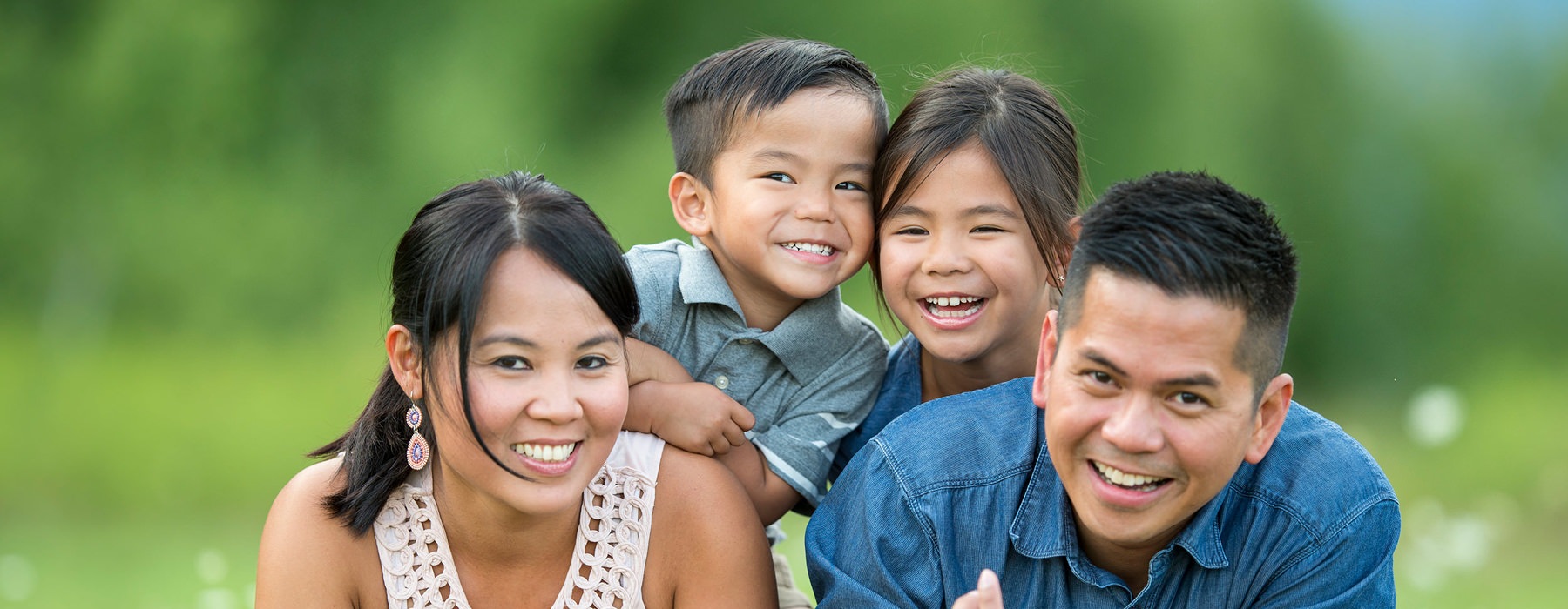 a young family poses for a family picture in park meadow